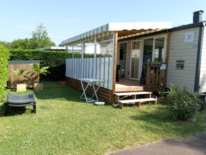 A small, single-story wooden house with a porch, a small deck, and a fenced backyard. - Getaway to Oléron - Fully equipped mobile home just a stone's throw from the beach   (Saint-Georges-d'Oléron)