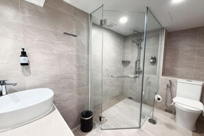 Une salle de bain moderne avec une douche à parois de verre, un lavabo sur pied et des toilettes.