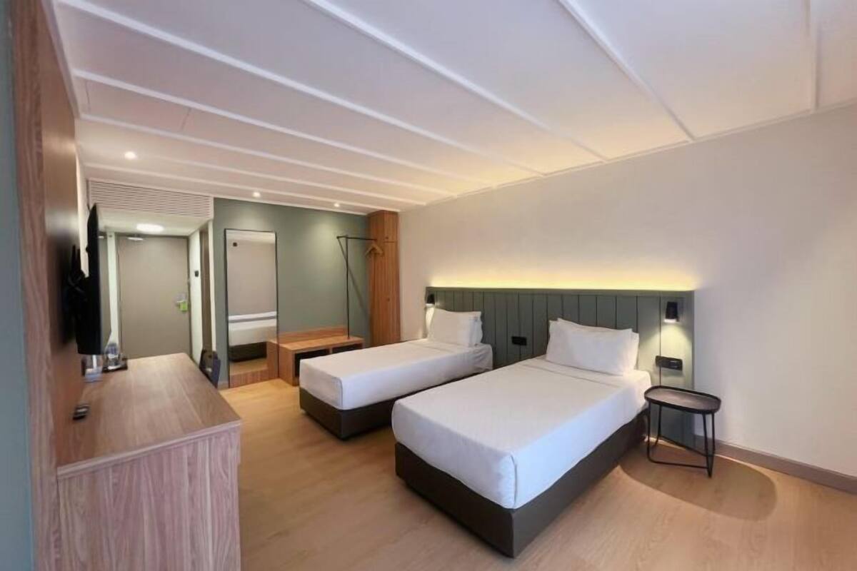 Een hotelkamer met twee bedden, een bureau, een stoel en een televisie.