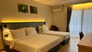 Une chambre d’hôtel avec deux lits, un bureau et une chaise. Il y a deux climatiseurs fixés au mur et une fenêtre avec des rideaux.