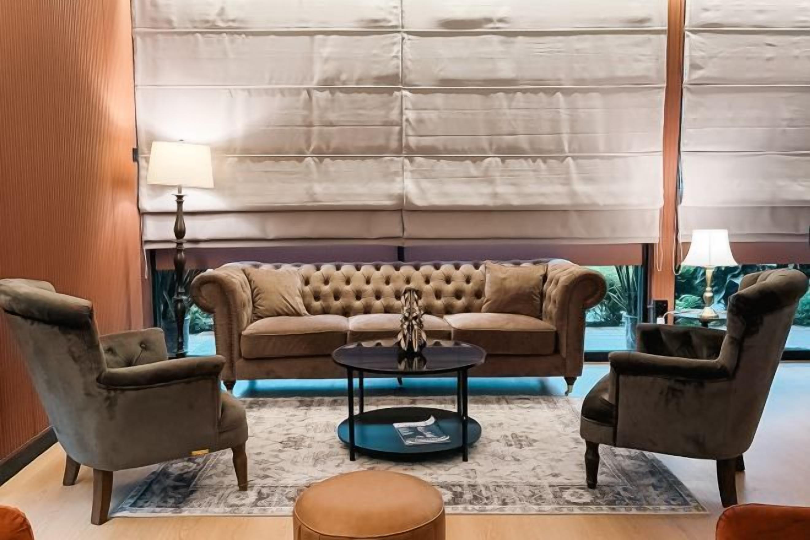 A living room with a tufted sofa, two armchairs, a round coffee table, and a patterned rug.