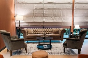 Ein Wohnzimmer mit einer gepolsterten Couch, zwei Sesseln, einem runden Couchtisch und einem gemusterten Teppich.