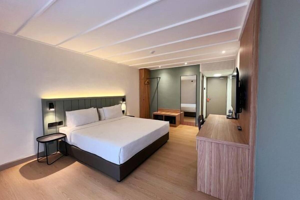Een moderne hotelkamer met een groot bed, nachtkastjes, een spiegel en een televisie.