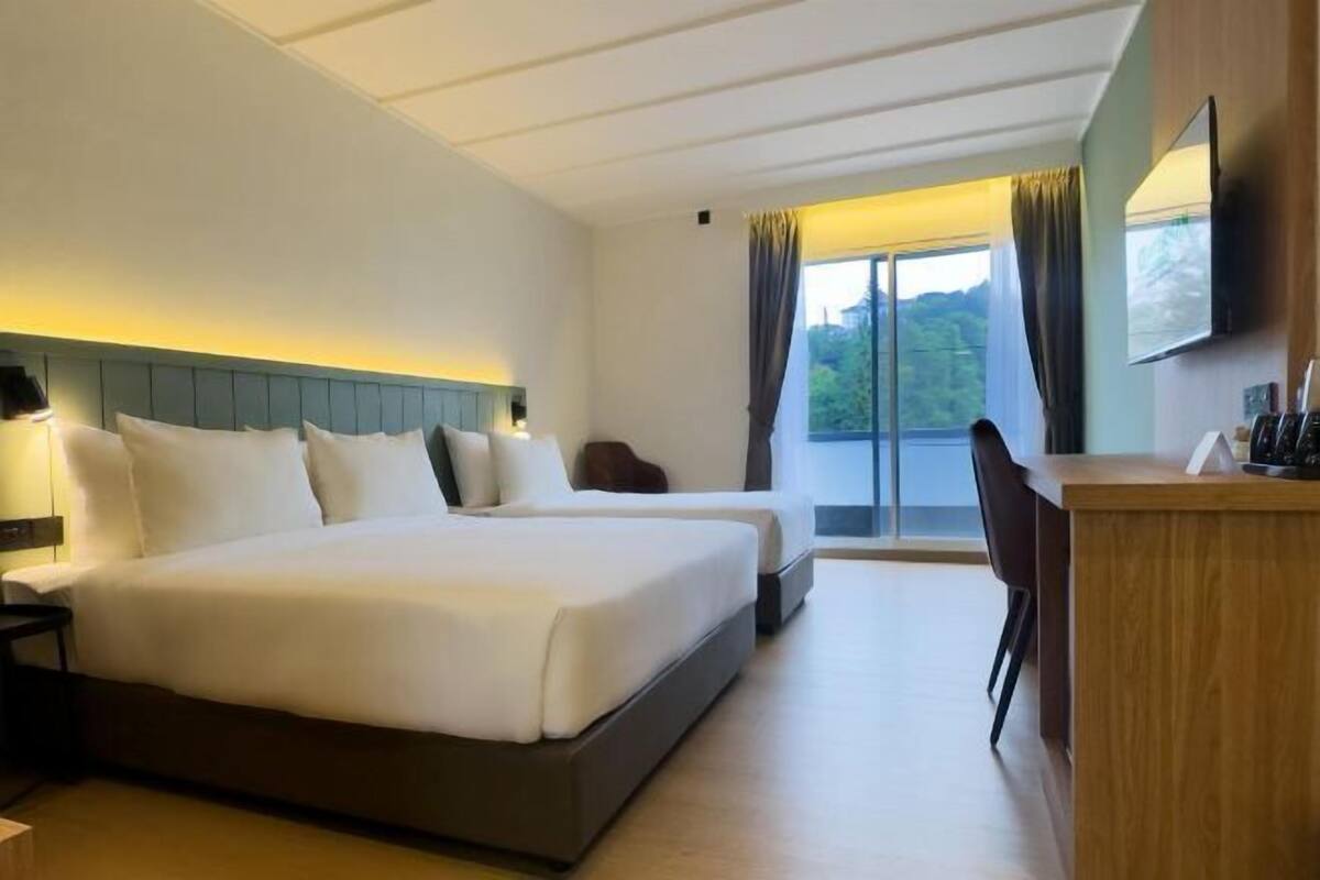 Een hotelkamer met een groot bed, een bureau en uitzicht op de omgeving.