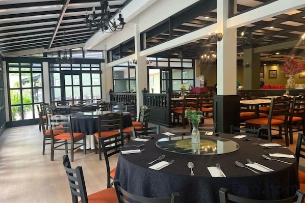 A restaurant with round tables, chairs, and a glass-top table.
