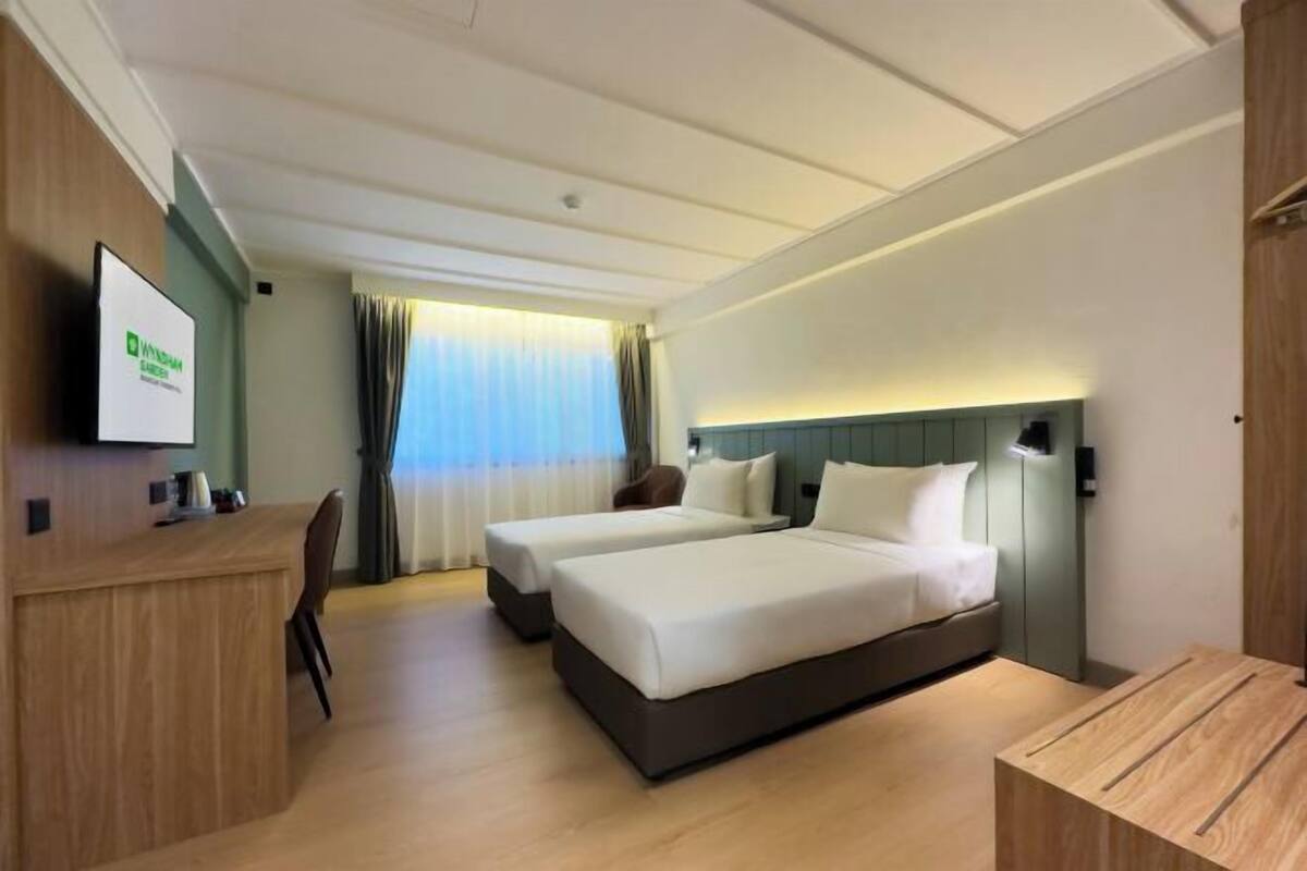 Een hotelkamer met twee bedden, een bureau, een stoel en een televisie.