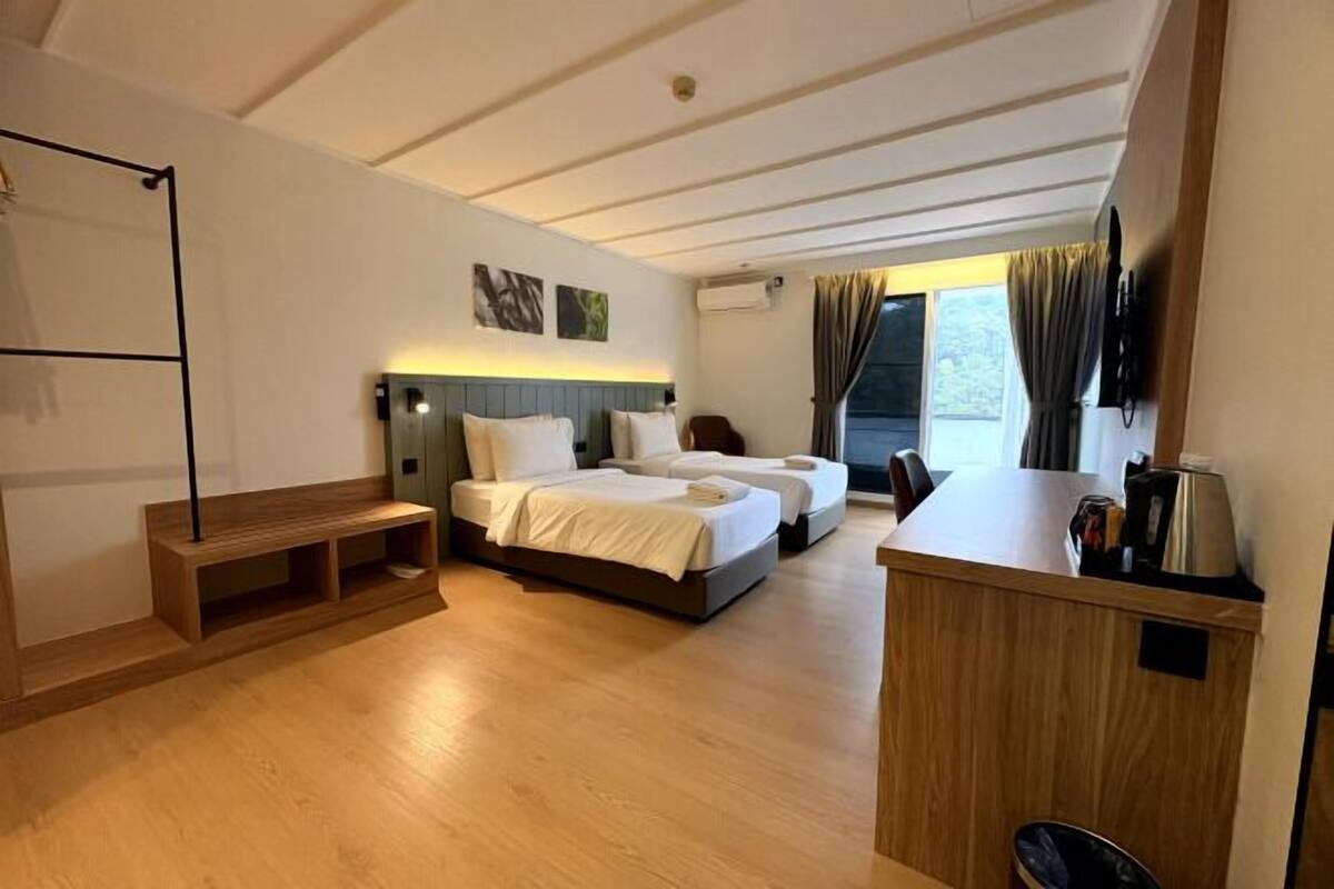 Een hotelkamer met een bed, een bureau en een raam met gordijnen.