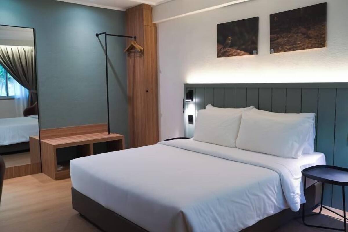 Een moderne hotelkamer met een groot bed, een nachtkastje, een spiegel en kunst aan de muur.