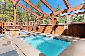 Eine Poolterrasse aus Holz, umgeben von Bäumen.