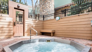 A hot tub area with a wooden fence, a stone wall, and a metal railing. - Large One Bedroom in Great Location! (Breckenridge)