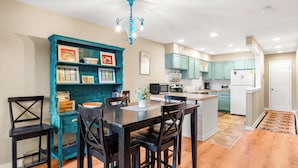 A kitchen with teal cabinetry, a dining table with chairs, a chandelier, and a microwave. - Large One Bedroom in Great Location! (Breckenridge)