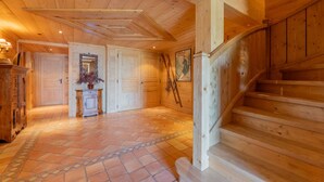 Een houten interieur met een trap, een open haard en een betegelde vloer.