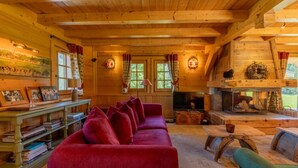 Een gezellig blokhutinterieur met een rode bank, houten planken, een televisie en een open haard.