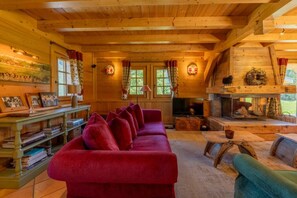 Ein gemütliches Blockhaus-Interieur mit einem roten Sofa, Holzregalen, einem Fernseher und einem Kamin.