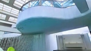An indoor swimming pool with a glass ceiling, a water slide, and a poolside area. - Condo near Makati with Free pool & Rockwell View (Mandaluyong City)