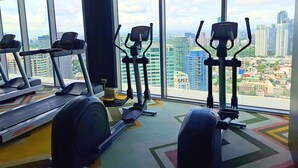 A gym with treadmills, elliptical machines, and a colorful floor pattern. - Condo near Makati with Free pool & Rockwell View (Mandaluyong City)