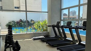 Ett gym med löpband, hantlar och en viktbänk.