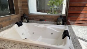Ett rektangulärt bubbelbad med en kontrollpanel på höger sida, placerat mot en bänkskiva i granit.