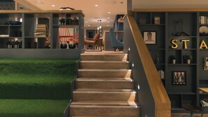 A modern interior with a staircase, bookshelves, and a green carpeted area. - Student Only College Green (Bristol)