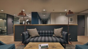 A modern lounge area with a sofa, two armchairs, a coffee table, and two floor lamps. - Student Only College Green (Bristol)