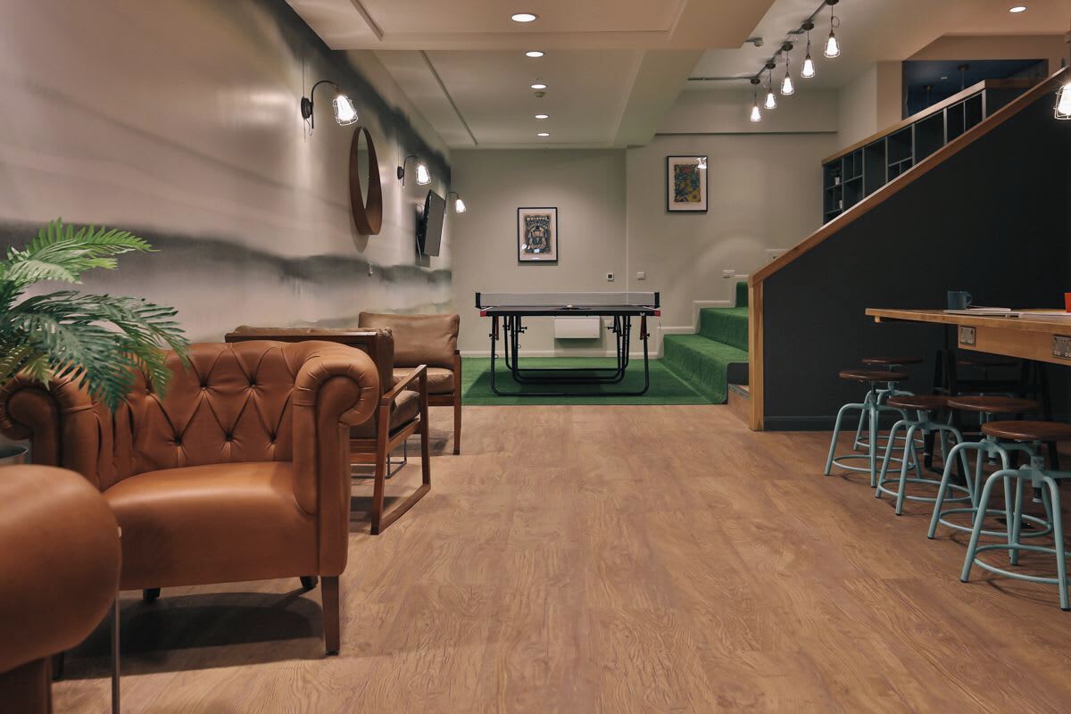 A modern lounge area with leather chairs, a ping pong table, and bar stools.