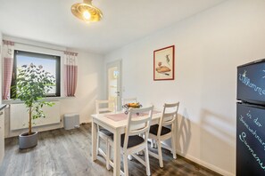 Un espace repas comprenant une table, des chaises, une plante en pot et un réfrigérateur.