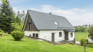 Une maison de plain-pied avec un toit en pente, un petit porche et une pelouse bien entretenue.