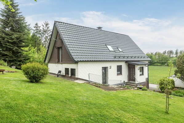 Une maison de plain-pied avec un toit en pente, un petit porche et une pelouse bien entretenue.
