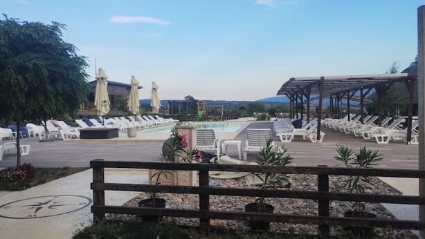 A poolside area with lounge chairs and umbrellas, a covered seating area, and a view of the mountains in the background.