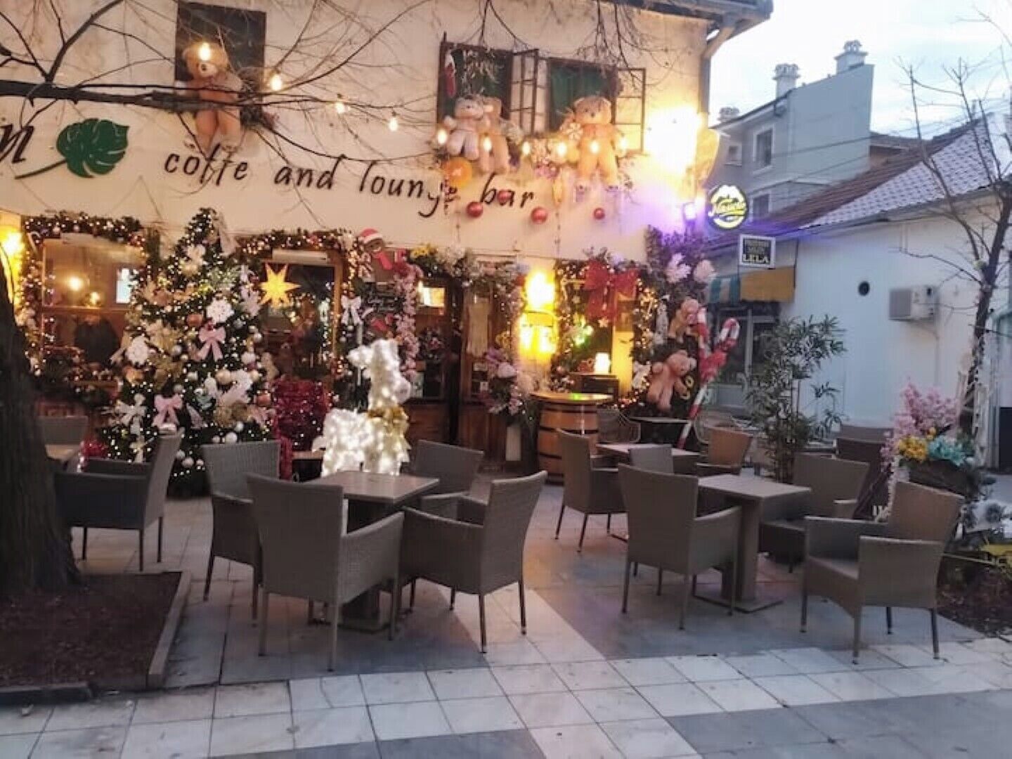 An outdoor seating area with tables and chairs, decorated with Christmas ornaments and lights.