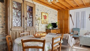 A dining area with a round table, chairs, a basket of fruit, and a stone wall.