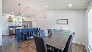 Een moderne keuken met een centraal eiland, barstoelen en een eettafel met stoelen.