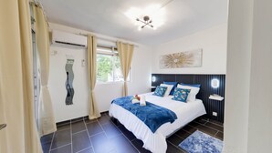 A modern bedroom with a bed, curtains, a window, and a ceiling light. - KATAL waterfront - T2 Comfort - Elegance (Sainte-Luce)
