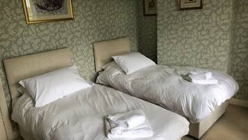 Two single beds with white linens and towels, a headboard, and a framed picture on the wall.