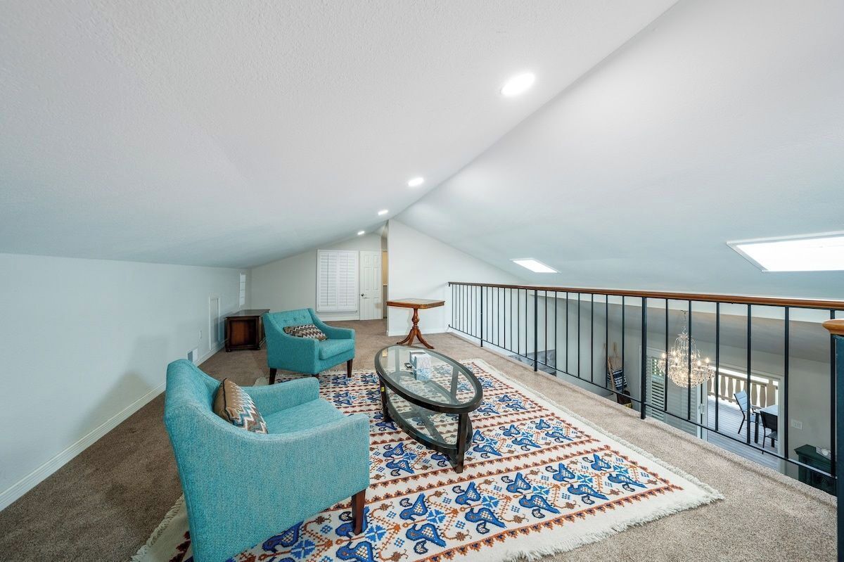 Un balcon spacieux avec une table en verre, deux chaises et un tapis à motifs.