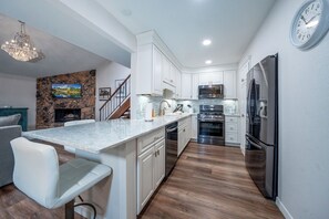 A modern kitchen with white cabinetry, a marble countertop, and stainless steel appliances. - Innsbrook Vacation Townhome 104 (Ruidoso)