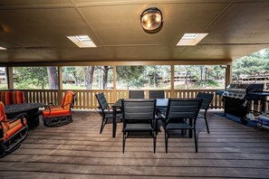 A covered outdoor area with a table and chairs, a grill, and a view of the surrounding landscape. - Innsbrook Vacation Townhome 104 (Ruidoso)