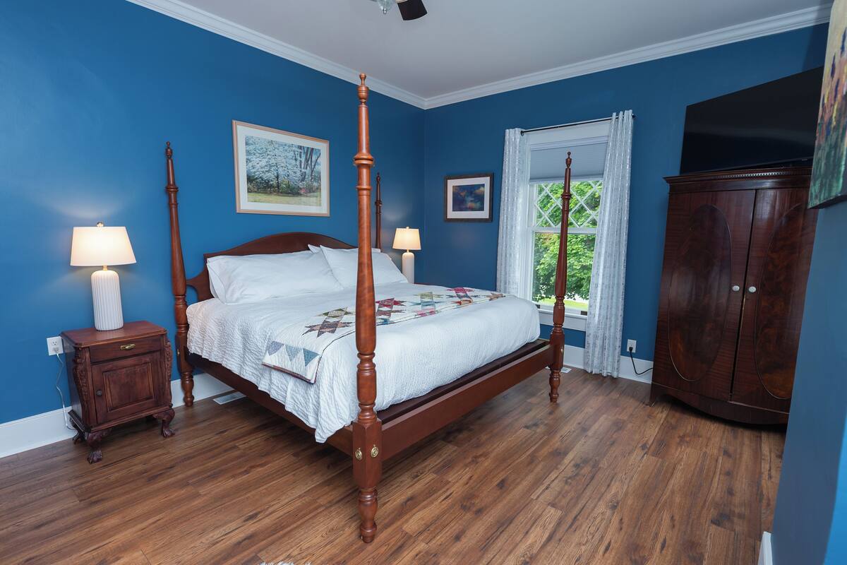 A bedroom with a four-poster bed, wooden nightstand, and a wardrobe.
