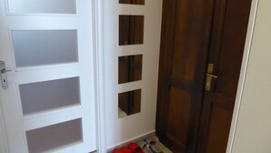 Un pasillo con una puerta blanca con paneles de vidrio esmerilado y una puerta marrón con picaporte dorado.