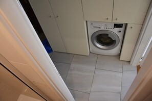 A laundry room with a washing machine, cabinets, and tiled flooring. - Beautifully Designed 1-bed Apartment by Vy Ehrad (Prague)