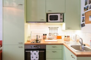 A kitchen with a microwave, stove, oven, and various kitchen utensils. - Beautifully Designed 1-bed Apartment by Vy Ehrad (Prague)