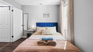 Un dormitorio con cama, mesita de noche, espejo y puerta.