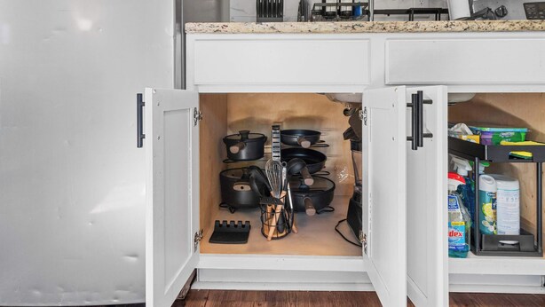 Una cocina con gabinetes blancos, encimera de granito y horno integrado.
