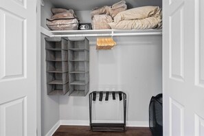 A storage closet with shelves, bins, and a foldable rack. - 3 Min to Downtown | 7 to Duke | Washer + Dryer (Durham)