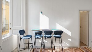 A room with a white door, a window, a table with chairs, and a patterned rug. - Antica Dimora Deluxe with Balcony, Wi-Fi and Air Conditioning (Napoli)