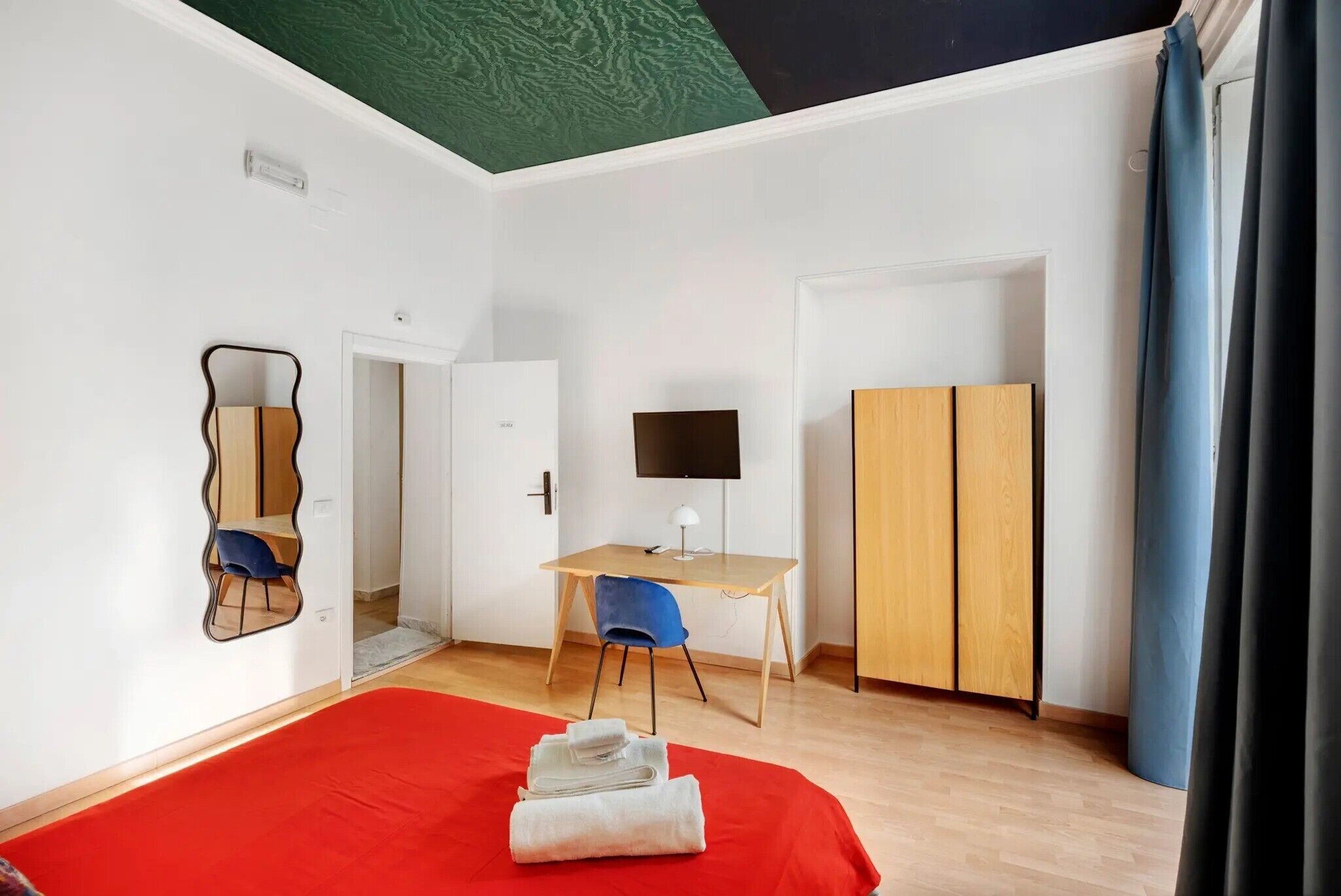 Een kamer met een bed, een bureau, een stoel, een televisie en een kledingkast.