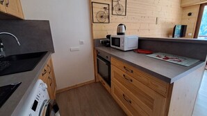 Cocina compacta con microondas, hervidor y un pequeño comedor.