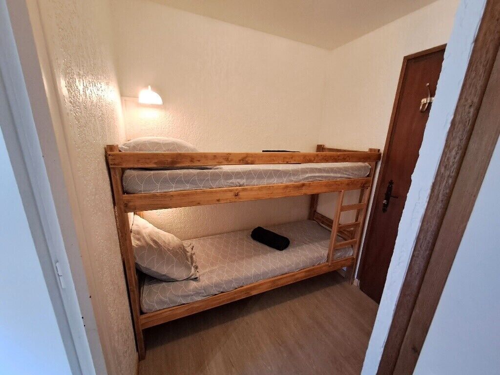 Een stapelbed in een kamer met een deur en een wandlamp.