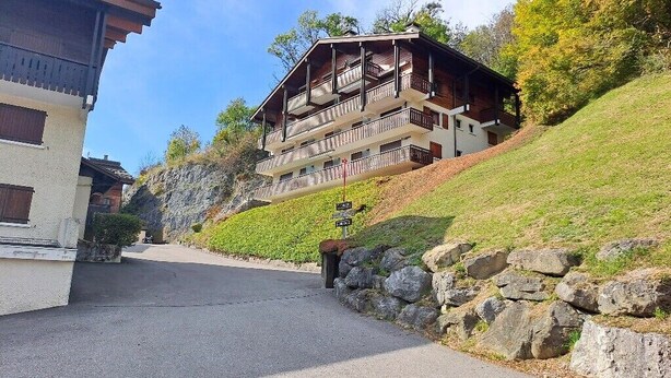Un edificio de varios pisos con balcones, un muro de piedra y un cielo despejado.