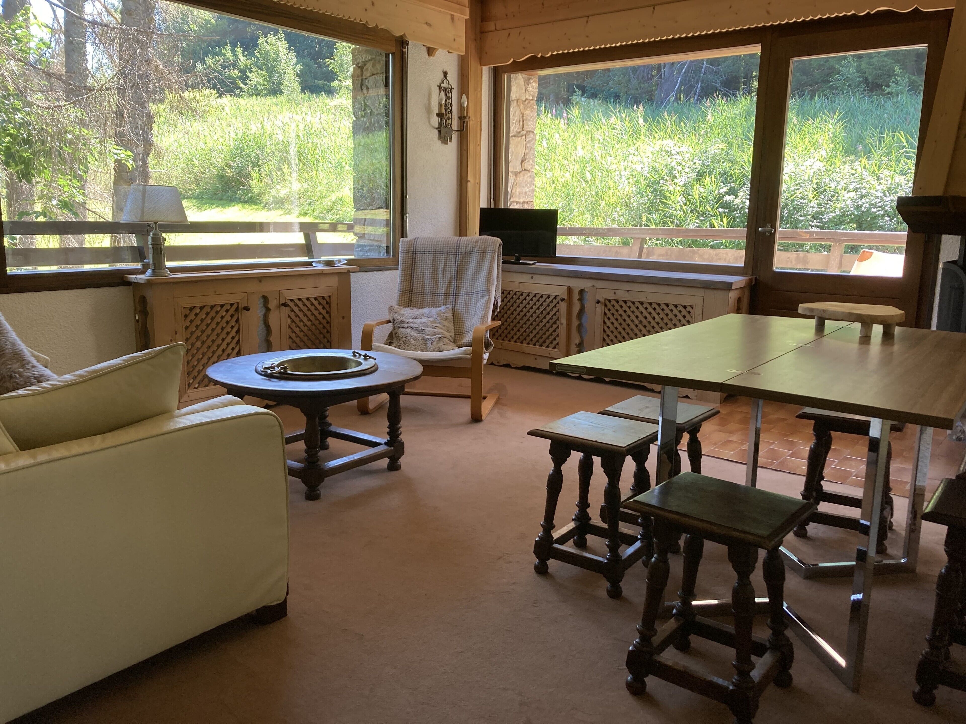 A cozy room with a sofa, a round table, a wooden chair, and a dining table.